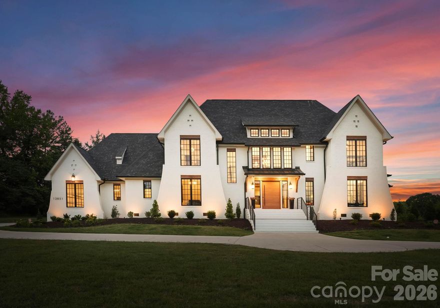 Designed for those who want every day to feel like an escape, this extraordinary custom estate overlooking tranquil pond views in the heart of Davidson delivers a rare blend of architectural sophistication, resort-inspired amenities, and elevated everyday living. Completed in 2024 and set on 1.33 pristine acres, the residence offers an exceptional lifestyle just moments from Davidson College, downtown Davidson’s beloved restaurants, boutiques, and everyday conveniences. Created to rival the experience of a private luxury resort, the outdoor living spaces are nothing short of spectacular. Framed by breathtaking sunset views and serene water vistas, the backyard retreat features a heated saltwater pool and spa, expansive fenced AstroTurf lawn, multiple lounging and entertaining areas, and a covered outdoor living pavilion complete with a fireplace and fully equipped outdoor kitchen offering the perfect setting for both intimate evenings and large-scale entertaining. Inside, refined craftsmanship and curated designer finishes define every space. Soaring ceilings, dramatic wood and metal beam accents, expansive sliding glass doors, oversized windows, and layered architectural details create a warm yet striking modern aesthetic throughout. The chef’s kitchen is equally impressive, showcasing premium stainless steel appliances, custom cabinetry, oversized island, and seamless open-concept gathering spaces thoughtfully designed for effortless entertaining and everyday luxury. The main-level primary suite serves as a private sanctuary featuring a spa inspired bath and expansive custom his and hers dressing rooms. Upstairs, three additional bedrooms are complemented by exceptional flex spaces including a recreation room with entertaining bar, bonus/media room, exercise studio, and custom bunk room offering remarkable versatility without compromising style or comfort. From its commanding presence and breathtaking backdrop to its meticulously curated interiors and resort-inspired grounds, this exceptional Davidson residence was thoughtfully designed to elevate every aspect of modern luxury living.