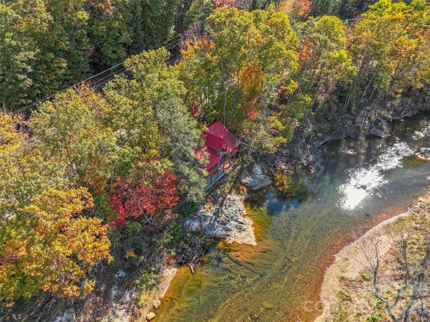 Rare, historic, hand hewn and chinking (1800's per seller) log cabin nestled on the South Toe River, that flows from Mt. Mitchell, highest mountain peak, east of the Mississippi River. This romantic log cabin was originally living off of Hwy 80 S, where the Laurel Heights community is. The history is, that it was a resting place for weary travelers to lodge overnight(per sellers and the info they have gathered, no documentation). It was moved(disassembled) in 1984, and reassembled, where its home is now, with over 1,000 feet of riverfront. The present owners has made many improvements assuring stability, with engineered, 200 cubic yards of concrete, metal roof, rustic beams, esthetic decorative wrought iron railings, with about 800 sq. ft of covered outdoor living/entertaining. It encompasses spacious 2 bedrooms, one with a wood stove, both have vaulted ceilings with beams, and wood floors. One and a half bath with claw ft. tub/shower, open style kitchen/dining with country brick floors. Generous living room with wood burning stove, and foyer, all viewing the river from both levels. Storage room with laundry on main level, outside of entrance door. Underneath is a large bonus area for outdoor entertaining, and river access for fishing, tubing, kayaking, or just absorbing nature in the serene riverside valley. The road is a quiet country road less traveled. This unique log cabin is a eccentric find for your paradise summer getaway or short term rental! Minimal damage from the storm and is now restored. The kitchen cabinets is a blank canvas, for your artistic touch. Possible studio apartment where shed is. Comes with furnishings and decor!