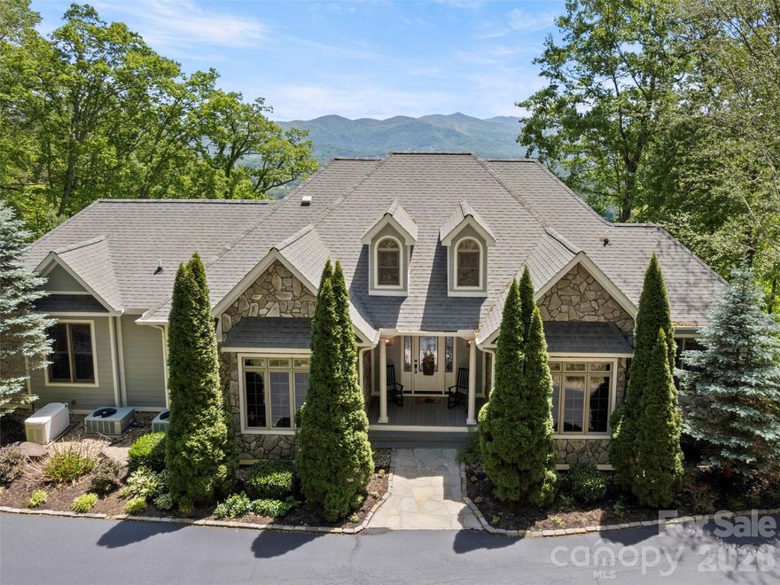 Experience elevated mountain living in this exceptional custom home nestled on 4 private acres in the gated community of Junaluska Highlands. Perfectly positioned to capture breathtaking layered views of Lake Junaluska, downtown Waynesville, and the surrounding Blue Ridge Mountains, this custom home blends comfort and the beauty of WNC . Designed for both everyday living and entertaining, the main level features a stunning great room with cathedral ceilings, cherry built-ins, a gas fireplace with handcrafted wood mantel, and expansive windows opening to a spacious partially covered deck where the views take center stage. The kitchen offers maple cabinetry, granite countertops, Travertine backsplash, breakfast bar seating, and a sunny breakfast area. A formal dining room with a tray ceiling creates an elegant setting for gatherings, while the main-level primary suite provides a peaceful retreat. A fourth bedroom currently serves as a home office. The lower level is ideal for guests and recreation, featuring two private ensuite bedrooms, a large family room with a gas fireplace, a wet bar complete with kegerator, beverage fridge, ice maker, and access to the stamped concrete patio. Thoughtful details throughout include crown molding, rich wood trim, tinted front windows, professionally designed & maintained landscaping by BH Graning, generator, paved level driveway, and oversized double garage. Located just minutes from Lake Junaluska, downtown Waynesville, and the Blue Ridge Parkway, Junaluska Highlands offers a serene mountain lifestyle with upscale homes, gated privacy, and unforgettable scenery at every turn.