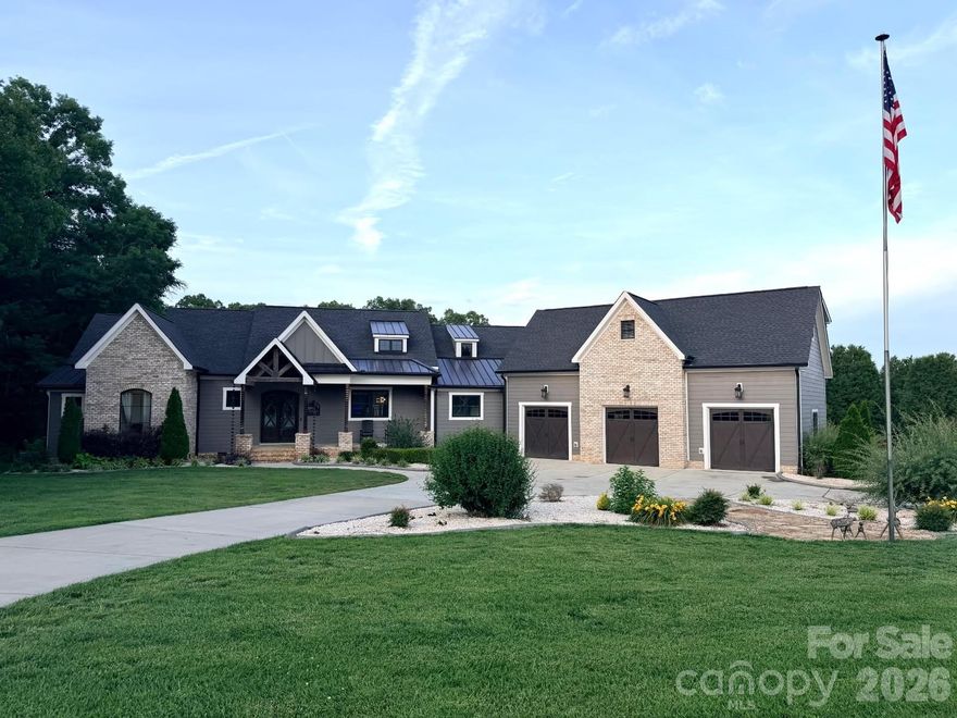 Welcome to a one-of-a-kind custom home where modern luxury, thoughtful design, and income-producing potential come together seamlessly. Built in 2020, this stunning property was designed for both elevated everyday living and unforgettable entertaining.
As you enter the home, the foyer immediately sets the tone with curated art display walls accented by dedicated lighting, creating a true gallery-style entrance. Rich black walnut hardwood floors run throughout the home, complementing the open-concept main living area that combines the living room, dining space, and chef’s kitchen into one expansive and inviting gathering space. The kitchen features luxury Dacor appliances, abundant workspace, and upscale finishes throughout. Anchoring the living room is a dramatic 60” direct vent linear stone fireplace with reclaimed hand-hewn beam mantle and custom built-ins.

Massive 12’ sliding doors open to nearly 1,000 square feet of composite decking, extending the living space outdoors and creating the ultimate entertainment area. Built-in surround sound speakers inside and out, home automation capabilities, dimmable smart switches, and whole-home mesh WiFi wiring elevate the home’s modern functionality.

The primary suite on the main floor is a true retreat featuring heated tile floors, elegant crown lighting, oversized walk-in closet systems with adjustable custom shelving and shoe storage, plus a hidden concealed storage space. The spa-inspired bath showcases an oversized walk-through rain shower with full body sprayers and luxury finishes throughout.

Two additional oversized bedrooms are also located on the main floor, each with their own private bathroom and spacious custom closets. The laundry room was designed with practicality in mind, offering built-in folding space, additional sink, and direct access to the custom dog wash station before entering the oversized 3-car garage.

Upstairs offers flexible finished living space perfect for work, play, or guests. A large built-in office area provides an ideal workspace, while the loft overlooks the living room through a stunning custom 3D metal railing design. The soaring ceilings create enough vertical space for an impressive 17’ Christmas tree centerpiece during the holidays. An additional upstairs room, currently used as a playroom, connects to a full bathroom and guest suite tucked quietly away for ultimate privacy.

Adding even more value, the detached studio apartment above the garage offers approximately 1,000 square feet of additional living space and incredible income-producing potential. Thoughtfully designed with separation and privacy in mind, the guest suite features its own dedicated parking area behind the garage, ensuring privacy for both owners and guests. The spacious studio includes a full kitchen with appliances, open-concept living area, laundry space, full bathroom, and additional nook currently used for extra sleeping accommodations. Whether used as an Airbnb, in-law suite, guest quarters, or private office, this space offers exceptional flexibility and can significantly offset ownership costs.

Additional upgrades and features include authentic 1600s Croatian wine press screws incorporated into the front entry design, on-demand hot water system, irrigation system, prewired exterior security cameras, built-in whole-home speaker system, reclaimed architectural details, expansive storage solutions, and a 3-stage water filtration system.

This is far more than a home — it’s a carefully crafted lifestyle property blending luxury, functionality, character, and opportunity into one unforgettable package