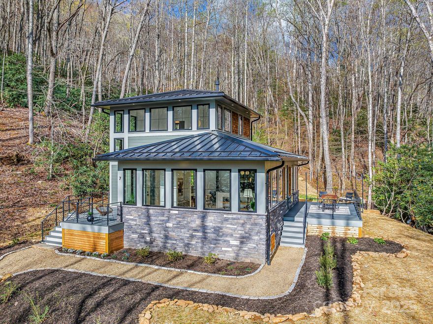 This custom-designed, brand new Pacific Northwest inspired home is a showstopper, offering a rare blend of peaceful seclusion & community connection in sought after East Asheville. Follow your own creek-lined private road to a modern retreat among trees, rhododendrons, & terraced stonework on nearly 2 acres. Enjoy natural light & forest views from every room through expansive & vaulted Jeld-Wen casement windows. Inside, lovely wide-plank oak floors, terrazzo tile, & designer fixtures create a warm, modern feel complemented by built-in hardwood shelving, luxury stone surfaces, & an on-demand gas stove. The layout includes a bedroom on each level, two full baths, plentiful storage, & a private office space to work from home with gig internet. Step outdoors to creekside living & dining space. Enjoy the extra land to grow, play, or expand. All nearly 15 minutes from downtown Asheville & a short drive to groceries, restaurants, & more. Adjacent 2 acres available upon request. STR’s allowed.