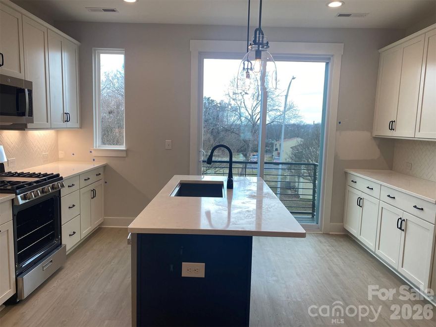 Craving close proximity to Uptown Charlotte & Camp North End? This townhome offers that & more. 4th floor w/ Bonus bedroom w/ powder & spacious rooftop terrace. 1st floor has a flex rm w/powder & 1-car garage plus driveway. Small deck off the kitchen has seasonal city skyline views. Kitchen features 42" white perimeter cabs w/ nautical blue cabs at the island, matte black hardware, LED under-cabinet lights, trash pullout, large undermount SS sink, quartz counters, & GE SS app w/ gas range. 3rd floor hosts both bedrooms & laundry. Guest bath has quartz counters & white cabinets. Premier Bath includes a nautical blue cabs, matte black hardware, quartz counters, & tiled shower with semi-frameless glass & shampoo niche. LVP flooring is throughout 1st & 2nd floors, plus 3rd floor landing, with oak treads on all stairs. Tile in full & half baths (excluding 2nd floor powder) & laundry. 3 ceiling fans; 9' ceilings throughout. Walking distance to bars, restaurants, events, and more!
