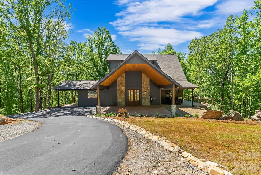 Welcome to your mountain top retreat on 7-acres. This exceptional 2024-built home offers the perfect blend of privacy, luxury, and modern efficiency. A gated entrance welcomes you along a graded gravel road leading to a paved circular drive setting the tone for the impressive design and thoughtful details throughout this 4,252-square-foot home.  A spacious entry off the covered porte cochere—equipped with two EV chargers—adds both function and style.  Step inside to a grand open great room featuring soaring ceilings and dramatic floor-to-ceiling windows that frame breathtaking natural surroundings and flood the space with light. Blue Ridge views open in the winter but once leafed out, the tress create a private sanctuary. The heart of the home is a chef’s kitchen outfitted with quartz countertops, abundant cabinetry, an induction range and  double refrigerator/freezers. The main-level primary suite is complete with a double-sided tiled shower, dual sinks, and an expansive walk-in closet conveniently connected to the laundry room with built-in storage. Upstairs, a versatile loft space is complemented by a pocket office and two generously sized bedrooms sharing a full tiled bath. One bedroom features a walk-in closet with a charming access door to a finished attic space—perfect for storage or a creative hideaway. The lower level expands the living space with a large recreation/family room, a full bath, and an additional flex room ideal as a guest bedroom or office. Step out to the lower patio, already wired for a hot tub and enjoy outdoor living off the main level with covered and open wraparound decking, perfect for dining & relaxing. Exterior amenities, including additional covered parking, a gravel RV pad with well and septic hookups, and a level area previously used as a horse riding ring. Sustainable and practical features include Tesla solar panels with back up battery, power and plumbing for a whole-house wood-burning furnace, fruit trees, and a storage shed. This one-of-a-kind property delivers modern mountain living at its finest—private, quiet &  designed for comfort. Just 10 minutes to downtown Morganton for shopping, restaurants and entertainment. Less than 10 minutes to I-40 access-1.5 hours to Charlotte and one hour to Asheville.