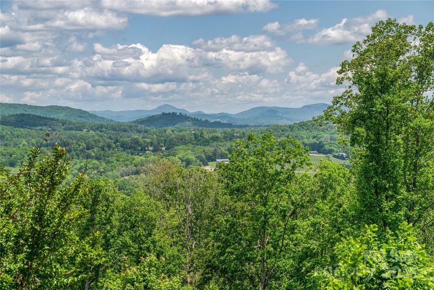 Perched at over 2,200 feet in elevation, this premier homesite in The Boulders—Western North Carolina’s sought-after gated mountain conservation community—offers sweeping, year-round views of the Blue Ridge Mountains. Set on Curtain Bluff, the gently sloping terrain is perfectly suited for a custom-designed mountain retreat. All essential utilities are in place, including underground power, natural gas, fiber optics, and city water; septic is needed. With no required timeline to build, this is a rare opportunity to create your dream home at your own pace. Just six minutes to Hendersonville’s charming Main Street and under 25 minutes to Asheville, the location balances seclusion and convenience. Residents enjoy a peaceful, nature-forward setting within a community that celebrates thoughtful design and environmental preservation. For those seeking expanded possibilities, the adjoining homesite is also available—offering added privacy or space for a second dwelling.