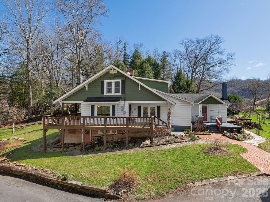 Classic farmhouse with gardens, porches, and flexible spaces, this 1920s home is full of character and possibility on 1.1 unrestricted acres between Waynesville and Asheville. It offers the country feel buyers want with easy access to town, commuting routes, and the best of Western North Carolina. Inside are 3 bedrooms and 3 baths, including a main-level primary suite with walk-in closet and nearby laundry. The light-filled kitchen with custom island and adjoining dining area creates a natural gathering place, while a family room and separate living room provide options for media, work-from-home, play space, or quiet reading. Character details, warm wood tones, and natural light add to the inviting feel, with a floor plan that works well for both everyday living and hosting guests. Outside, the wrap-around porch is ideal for rocking chairs, morning coffee, and sunset views, and the raised garden beds plus open yard offer space for flowers, veggies, and room for chickens or small-scale homesteading. A detached 2-car garage with flex room above(not included in finished sq ft)—perfect for an office, studio, gym, hobby room, or guest overflow—pairs with a separate 2-car carport for additional covered parking or storage, creating a classic farmhouse lifestyle with room to spread out and enjoy the land.