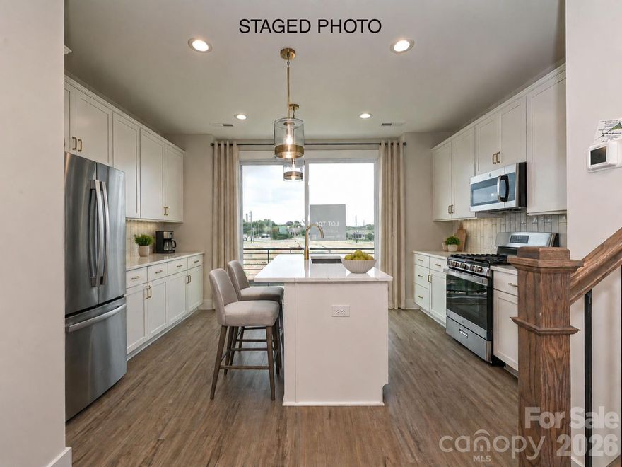 LOCATION! 4-story townhome across from Camp North End & minutes to Uptown! Highlights include 9' ceilings throughout, a 2-car tandem garage (plus on-street parking is available), on-trend lighting & design features, & a versatile 4th floor, including a Bonus bedroom w/ half bath & spacious rooftop terrace w/ TREX decking. Kitchen features white painted 42" cabs w/ brushed gold hardware, a pantry cabinet, trash pullout, LED under-cabinet lights, quartz counters, large SS undermount sink, & GE SS app w/ gas range. Small deck off kitchen w/ TREX decking. 3rd floor hosts both bedrooms & laundry closet with tile floor. Premier Suite has an en-suite bath w/ light grey cabs, satin nickel hardware, quartz counter, tiled floor, & tiled shower with semi-frameless enclosure. Guest bath has white cabinets, quartz counters, and tiled floor. LVP flooring is throughout the 1st & 2nd floors, plus 3rd floor hall. Oak treads on all stairs. 52" ceiling fans are included in the living room and premier suite.