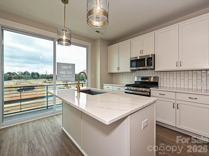 LOCATION! 4-story townhome across from Camp North End & minutes to Uptown! Highlights include 9' ceilings throughout, a 2-car tandem garage (plus on-street parking is available), on-trend lighting & design features, & a versatile 4th floor, including a Bonus bedroom w/ half bath & spacious rooftop terrace w/ TREX decking. Kitchen features white painted 42" cabs w/ brushed gold hardware, a pantry cabinet, trash pullout, LED under-cabinet lights, quartz counters, large SS undermount sink, & GE SS app w/ gas range. Small deck off kitchen w/ TREX decking. 3rd floor hosts both bedrooms & laundry closet with tile floor. Premier Suite has an en-suite bath w/ light grey cabs, satin nickel hardware, quartz counter, tiled floor, & tiled shower with semi-frameless enclosure. Guest bath has white cabinets, quartz counters, and tiled floor. LVP flooring is throughout the 1st & 2nd floors, plus 3rd floor hall. Oak treads on all stairs. 52" ceiling fans are included in the living room and premier suite.