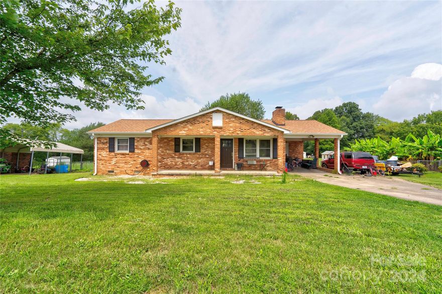 This is a one story brick home with covered front porch, and single carport with storage room.  This 3 bedroom, 1 bath home is on a .75 acre lot. There is a wood burning fireplace in living room.  Outside you will find a rear deck, fenced in backyard and a large storage building.