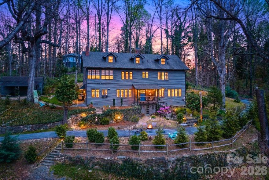 Historic “Mostly Hall” sits just steps from the heart of Tryon, offering a rare combination of walkable convenience, privacy, and enduring architectural significance. Originally built circa 1912, this landmark residence reflects the charm of an English cottage with Cape Cod influences, now thoughtfully reimagined for modern living.

Set on over an acre of mature landscaping with stone walls and winding garden paths, the home feels tucked away and serene, yet remains moments from Tryon’s shops, restaurants, and cultural scene.

Inside, the home has been carefully updated while preserving the craftsmanship that defines its character. Wide archways, exposed beams, rich hardwood floors, and original millwork create a sense of warmth and continuity throughout. Natural light pours through classic Craftsman-style windows, highlighting details like beadboard, crown molding, brick accents, and custom built-ins.

The main living spaces flow effortlessly, anchored by a charming brick fireplace and extending into a gracious dining room ideal for gatherings. A sweeping staircase adds architectural presence, leading to well-appointed upper levels.

The kitchen blends timeless design with modern function, featuring Carrara marble countertops, custom cabinetry, gas range, and stainless appliances, complemented by exposed brick and open shelving.

Upstairs, three bedrooms and three baths include a spacious primary suite with sitting area, along with a sleeping porch and dedicated laundry.

A standout feature is the private, fully equipped guest suite with its own entrance. Complete with kitchenette, living area, bedroom, and full bath, it offers exceptional flexibility as a guest retreat, extended living quarters, or income-producing opportunity.

Fully updated, walkable to town, and steeped in Tryon history, this is a rare chance to own a property that offers both lifestyle and long-term value.