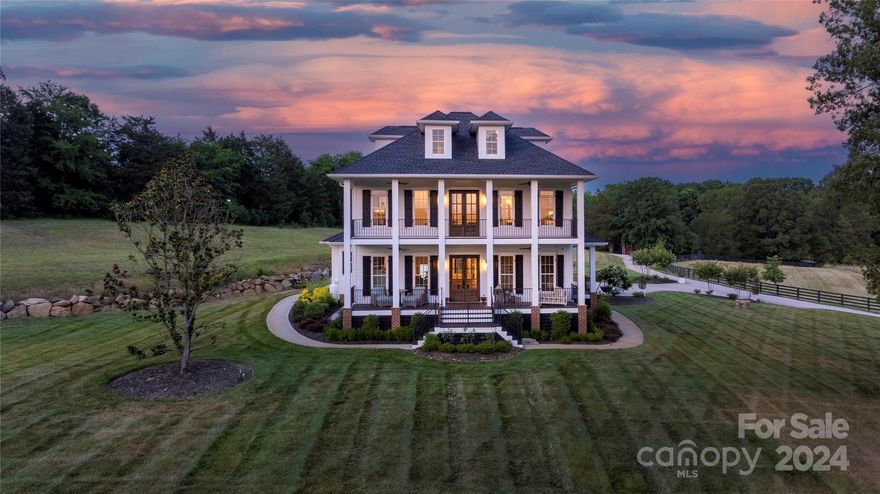 Welcome to your dream 8 acre homestead, in the most stunning setting, complete with a gorgeous Charleston-style home with oversized double front porches, a gated entrance, versatile outdoor entertainment areas with an outdoor fireplace and firepit, a fully stocked pond and a barndominium! This spacious residence offers a seamless blend of comfort and style, with high-end features and exquisite details throughout. Gourmet kitchen with custom cabinetry, marble countertops, a reclaimed barnwood hood, and inviting center island. The primary suite on main features a brick walk-in shower, a 2-tone custom claw-foot tub and walk-in closet. The barndominium lies adjacent to the main home and features four bedrooms, two full baths, a full kitchen, bar, living room, laundry, a shop and 3 bays with one pass through! If you’re looking for all the comforts of a luxury home with the land for livestock and to entertain, this is your tranquil oasis. 15 miles to Winthrop University located in Rock Hill.