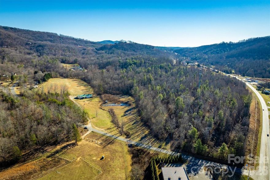 Set on 17.88 acres just minutes to downtown Morganton, this unique property offers the perfect blend of versatility and convenience. A standout feature of this property is the expansive building (4,057 sf) providing approximately 3,630 square feet of garage/workshop space along with 427 square feet of finished living quarters. The living quarters feature a kitchenette, bedroom and bathroom ideal for guests, a home office or future expansion. Enjoy a fenced pasture, small creek and a pond creating a peaceful setting. A rare opportunity to own acreage close to town with flexibility to fit a variety of lifestyles. Whether you’re seeking a private retreat, a versatile workspace with living quarters, or land ideal for horses and livestock, this property offers endless possibilities.