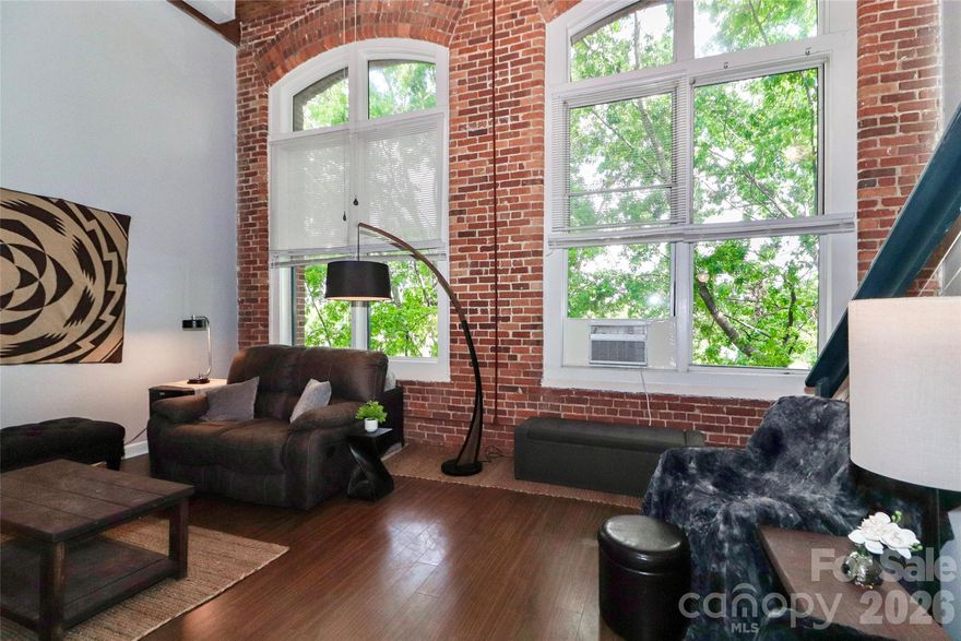 Step into a rare blend of historic charm and modern style in this stunning industrial-style condo, located just minutes from Uptown Charlotte. Set within one of Charlotte’s original mill buildings, this third-floor unit is filled with natural light from dramatic 12-foot industrial windows and showcases exposed brick, original wood beams, and soaring ceilings that make an unforgettable first impression. The open-concept living space features solid-surface flooring, a sleek cable rail system, stainless steel appliances, and kitchen island—perfect for entertaining or everyday living. Enjoy the peace of a quiet, wooded view while being part of a vibrant and unique community. The main level offers a comfortable primary bedroom, while the upstairs loft provides flexible space ideal for a second bedroom, home office, or workout area. Residents also enjoy access to a full-service community laundry facility. This is a truly special opportunity to own a piece of Charlotte’s history with the modern comforts that today’s buyers want—all in a prime location close to dining, entertainment, and city life.