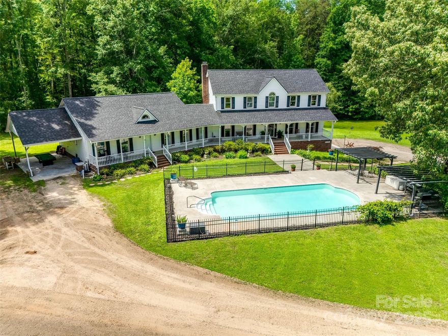 Welcome to this idyllic farmhouse retreat set on 13.14 acres of peaceful countryside, complete with a long winding trail through the trees in back affectionately named “Horseshoe Trail.” The home greets you with a huge rocking chair front porch and tree swing that invites slow mornings and sunset views. The main house features 4 bedrooms, 2.5 baths, dining room, office, family room and kitchen that serves as the heart of the home. Downstairs, the basement offers generous storage, bathroom, workout/additional living area. Outdoors, enjoy the in-ground swimming pool, fruit trees, a barn/shed, and a flock of chickens that can stay. An attached single-level wing/ apartment provides flexibility with 2 bedrooms, 2 baths, its own kitchen, laundry, family room, separate entrance, private deck, and carport—ideal for guests, extended family, or rental potential. This property is the perfect blend of charm, space, and opportunity to make your farmhouse vision a reality.