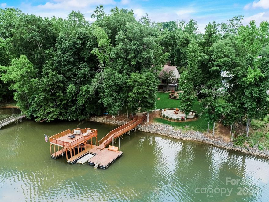 Welcome to this stunning Mountain Island Lake retreat, a haven of comfort and convenience. With breathtaking lake views and beautiful landscaping, this serene property is a true escape from the hustle and bustle. The multiple decks, covered porches, and terraces make this property unique. Each space is designed for comfort and enjoyment, from the private spa terrace off the kitchen to the large deck for entertaining and a stone fire pit for hanging out by the lake. Inside, the open great room with exposed beams, custom built-ins, and the renovated kitchen will leave you in awe. The large primary bedroom has a fireplace, dual closets, and a luxury bathroom. Custom closet systems throughout for organizing. The finished basement is an entertainer's dream, with a media room, a wet bar, a pool table, and a spacious living area. The lake amenities include the 2-story floating dock and deep water for swimming. This home is an absolute must-see, offering a relaxing lake lifestyle.