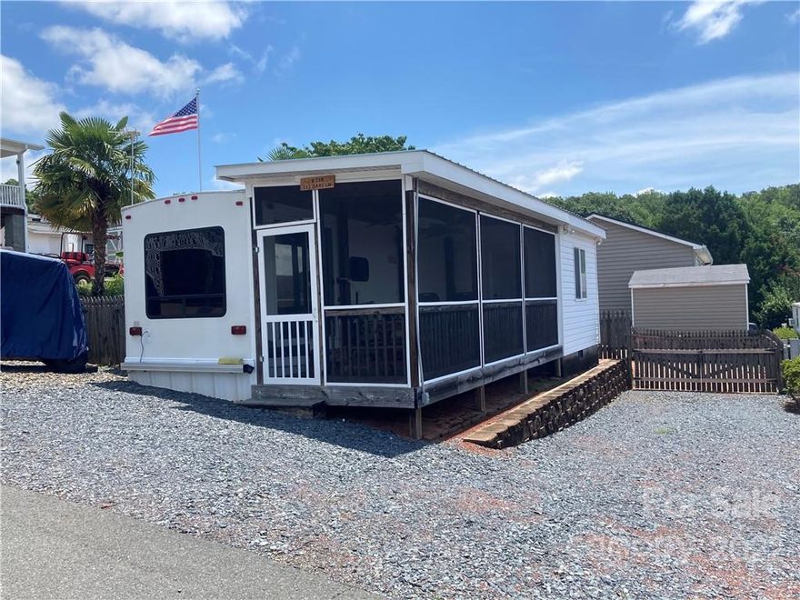 This lot B138 in Badin Shores Resort includes a 2005 Sierra Travel trailer with a 10ft. X 8ft. room addition set up as a bedroom with a built in closet. It also includes a 22 X 8 covered screened porch, a gated fenced storage area, and a bricked rear patio. This home is in the area of Badin Shores Resort with great views.  Dare Lane is just off of Grand View.  This home has a great view of Badin Lake year around from the porch and patio area too.  The parking is sufficient to allow both vehicle and boat parking. The owner has recently replace the original trailer roof with a commercial grade rubber roof and added hard metal covering on the slide. The Trailer Roof AC unit is also new. The room addition and screened porch has a low maintenance metal roof. The original water heater and refrigerator has been recently replaced. Badin Shores Resort is a gated lake resort with many amenities such as a pool, marina, boat ramp, clubhouse, putt-putt, pavilion, tennis and Basketball courts