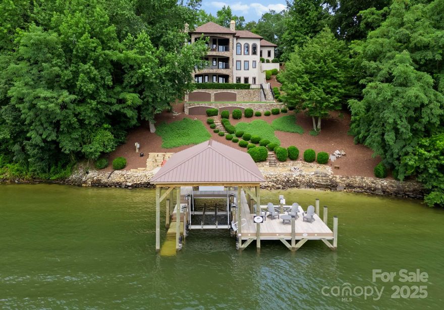 NEW PRICE BELOW APPRAISED VALUE!! Incredible long range water views from your Private Island Estate! This exquisite 3-story masterpiece on Lake Norman offers stunning panoramic waterfront views from every room. Located on prestigious, gated Windemere Island, this elevator-ready property features a new custom dock (2023) w/covered boat slip, boat lift & jet ski lift + private beach area at the shoreline. Grand foyer welcomes you w/marble flooring & striking 3-story Brazilian Cherry & wrought iron staircase. Main level designed for seamless entertaining, boasting a spacious chef's kitchen & living room with custom fireplace. French doors off the kitchen lead to 1 of 3 covered, tiled balconies, each complete w/double ceiling fans. Owner's Suite on middle level provides private balcony. Basement level offers 2 en-suite bedrooms and two large rooms that can be customized to suit your needs. Beautiful, finished garage w HVAC. Elevator ready!