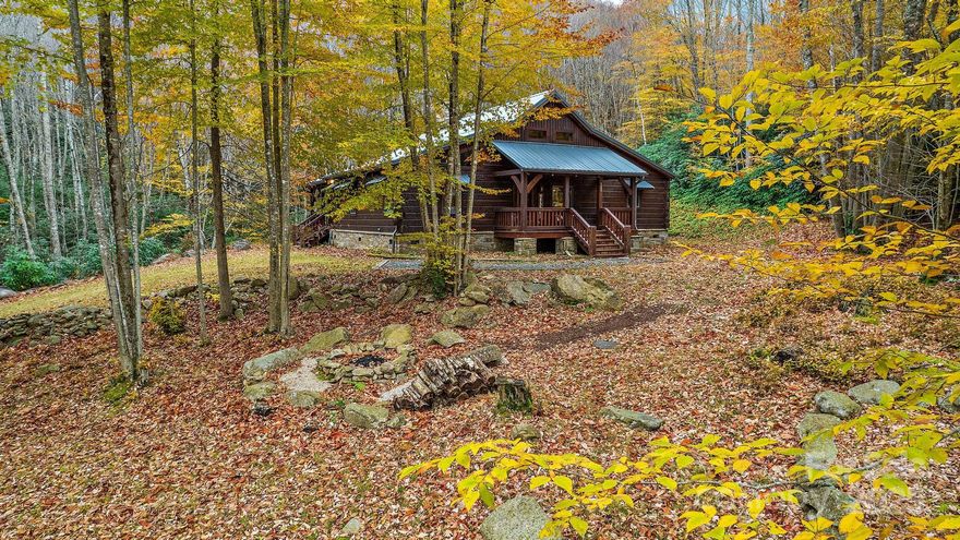 Experience mountain living at its finest in this beautifully crafted log home on a wooded 1 acre homesite in Beech Mountain. Currently operating as a successful, fully-furnished Airbnb, this turnkey property offers an effortless transition for investors, second-home buyers, or those seeking a serene primary residence. The warm and inviting interior features an open floor plan with vaulted ceilings and a dramatic floor-to-ceiling stone wood-burning fireplace as the focal point of the living room. The kitchen is thoughtfully designed with a live-edge wood island countertop, stainless steel appliances, a large copper sink, and high-end finishes throughout, providing both function and mountain lodge charm. The spacious primary suite offers direct access to the back deck and includes a luxurious en-suite bath featuring a freestanding copper soaking tub and double copper vanities. Secondary bedrooms are equally inviting, each with vaulted ceilings and ample space for guests. Outdoor living is where this home truly shines. A stunning second wood-burning fireplace anchors the expansive covered deck, great for gathering, dining, or simply relaxing among the trees. Enjoy the hot tub, porch swing, and multiple seating areas that make this home a year-round retreat. The wooded setting offers privacy and a true mountain escape, while still being convenient to Beech Mountain attractions, skiing, hiking, and shopping. Whether you continue its proven rental performance or keep it as your own getaway, this home offers timeless style, comfort, and an unforgettable setting. Schedule your showing today!