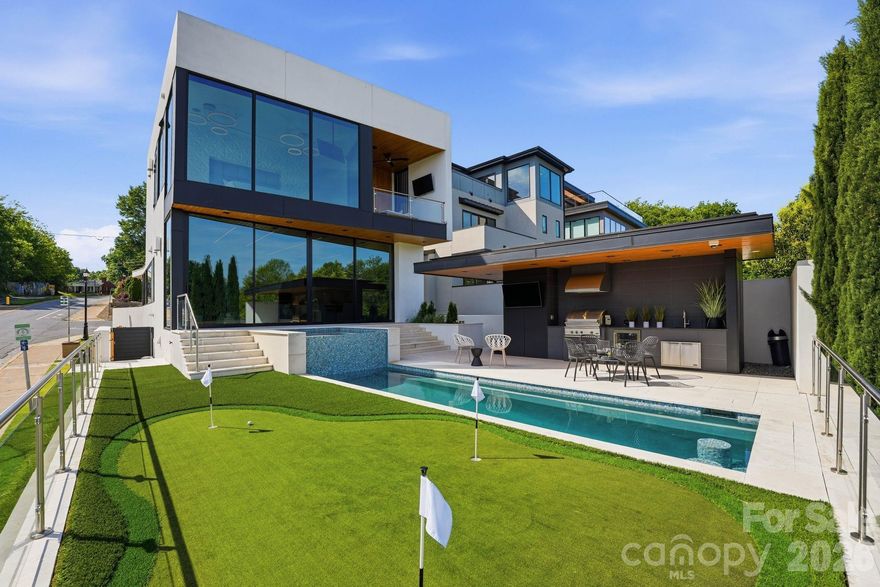This exceptional modern residence blends steel and glass to create a striking architectural statement, offering arguably the best breathtaking Charlotte skyline views through dramatic floor-to-ceiling windows and three expansive patios. Designed for seamless indoor-outdoor living, the home features a one-foot-thick concrete wall, custom wood elements, and curated high-end finishes throughout. The open-concept layout includes a chef’s kitchen with integrated appliances, and walk-in pantry with pellet ice maker and refrigerator drawers, under counter and toe kick lighting while multiple living and entertaining spaces are wrapped in glass to maximize light and views. The primary suite showcases three walls of floor-to-ceiling glass, a private balcony, custom his and hers closets, and a spa-inspired bath with soaking tub, fireplace, and oversized shower. Additional highlights include a Savant smart home system, solar panels, guest suite, lower-level private bedrooms with en-suites, and a versatile upper-level entertainment space. Outdoor living is elevated with a resort-style pool featuring built-in seating, full outdoor kitchen, cabana bath, and custom putting green—all designed to capture year-round city views. Please see the attached features list for even more features. Agent is owner.