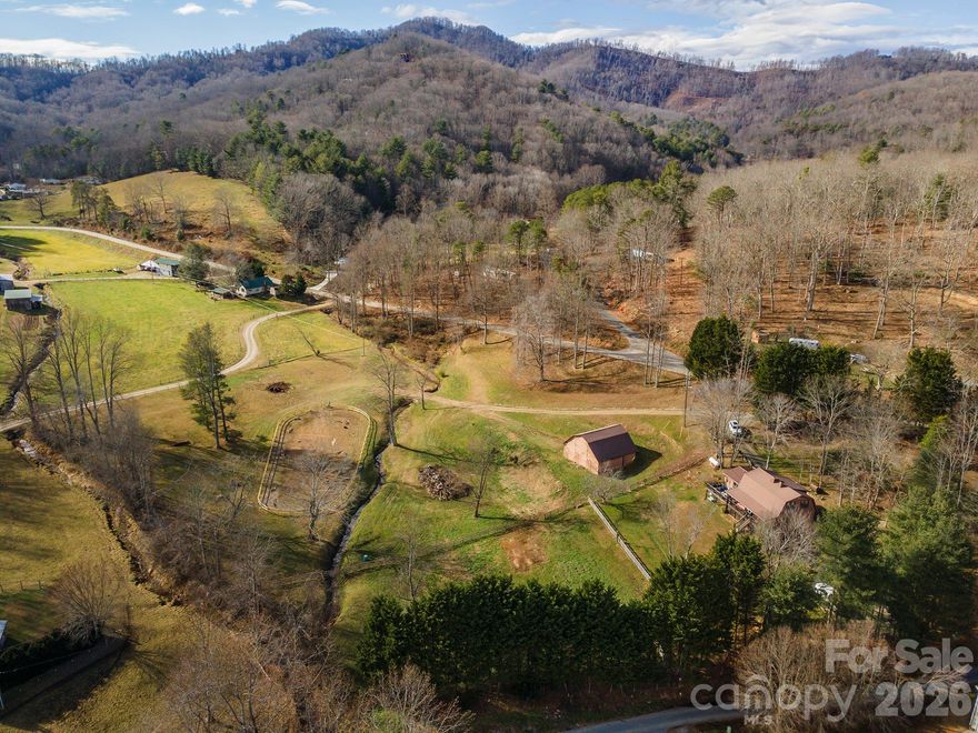 Tucked into a peaceful rural valley with sweeping mountain views, this one-of-a-kind equestrian property on Dix Creek has been a cherished home for horses, chickens, dogs, cats, and the people who love them for over 30 years.

The 4-stall barn is well-appointed with a tack room and hay loft, while a riding ring with new fencing gives you a dedicated space to ride and train — all set against a gorgeous mountain backdrop. The land is gently sloping and usable, offering the kind of valley acreage that's increasingly hard to find in Western NC.

The cabin radiates the kind of warmth that can't be manufactured — original wood floors, solid wood paneling, and exposed beams give it an authentic 1970s character that feels grounded and inviting. Step out onto the covered back porch and deck and you're rewarded with sweeping mountain views and a symphony of birdsong — the kind of morning that makes you forget there's anywhere else to be. 

The main floor features a wheelchair-accessible bedroom and full bath with exterior ramp, making it both charming and practical. Upstairs, three additional bedrooms and two updated bathrooms offer plenty of space for family and guests. The full unfinished basement provides generous storage today and real potential for a finished rec room, workshop, or entertainment space down the road.

Properties like this — with the acreage, infrastructure, and setting to support a true homestead lifestyle — rarely come to market.