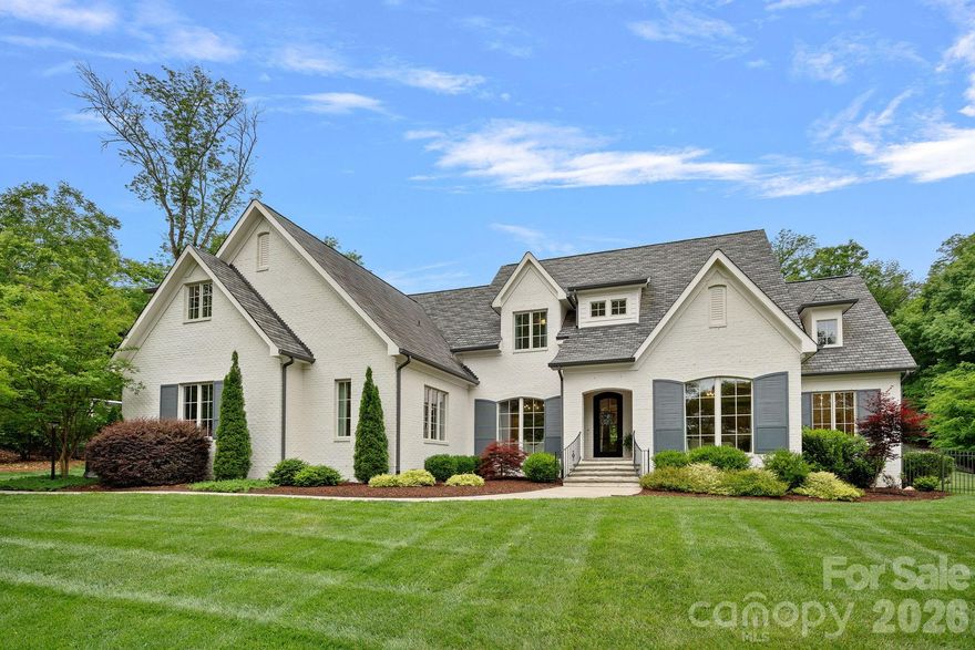 Situated on a picturesque 1.47-acre lot in Carmel Acres, this stunning custom-built home blends quality craftsmanship and timeless architecture with refined finishes and gracious living spaces. From the moment you enter, thoughtfully designed spaces unfold, capturing the home’s true elegance. At the heart of the home, a beautifully appointed chef’s kitchen opens to the family room and features Calcutta Gold marble countertops and backsplash, Wolf range, Sub-Zero refrigerator, Bosch dishwasher, a generous center island, and a bright, sunlit breakfast nook. The spacious family room centers around an elegant gas fireplace and surround, a stunning chandelier, custom shelving flanking the fireplace and French Doors that open to the covered rear porch – perfect for seamless indoor-outdoor living. The main level primary suite offers peaceful backyard views and a spa-like bath with beautiful cabinetry, a large walk-in shower, soaking tub and an expansive closet. A charming guest suite is also on the main level and is showcased by decorative wallpaper and paneled wall accents, a walk-in closet and a shared bath connecting to the front playroom/bedroom. The upper-level features generously sized secondary bedrooms, an office, a playroom, bonus room with en-suite bath, and fabulous walk-in attic storage areas. The fully fenced backyard offers an ideal setting for a future pool and features an impressive custom-built playhouse with deck areas – a wonderful retreat for outdoor play and enjoyment (The playhouse is not heated or cooled.). Convenient proximity to Southpark, Ballantyne, Stonecrest and I-485. A rare offering that embodies timeless appeal, thoughtful craftsmanship and elevated everyday living – a truly special home!