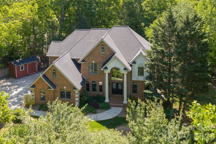 For those seeking space and access, 39 Windover Drive offers a rare combination of convenience, presence, and thoughtful design all within gated Poplar Ridge. The home unfolds across three well-defined levels, each crafted with intention. The main floor features hardwood floors, a dramatic two-story great room with a gas fireplace and custom built-ins, formal dining, a private office, and a main-level guest suite. The chef’s kitchen is equipped with premium appliances, including a Wolf cooktop and vented hood, KitchenAid double wall ovens, Bosch dishwasher, expansive island, and two walk-in pantries designed for both function and scale. Upstairs, the primary suite offers a large, private retreat with its own sitting area and fireplace, a four-seasons room currently being used as an exercise room, spa-inspired bath with jetted tub and tiled shower, and an oversized walk-in closet. Additional bedrooms include both ensuite and shared configurations, providing flexibility for family and guests. The lower level is dedicated to recreation and entertaining, complete with a private theater, game room with a wet bar, additional bed/bonus, full bath, and direct access to the fenced backyard. Outdoor living extends to a large back deck, brick patio with fireplace and raised garden beds, creating an inviting setting for gatherings. A three-car main-level garage, mature landscaping, storage shed, and proximity to community amenities further enhance this offering. Enjoy easy access with close proximity to the gate and a preferred setting directly across from the community park. Ideally located just minutes from South Asheville’s premier conveniences, including Whole Foods, Ingles, Publix, dining, shopping, entertainment, and the scenic Blue Ridge Parkway, the home offers a rare balance of private gated living and everyday accessibility.