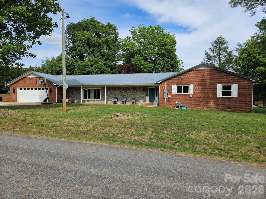Beautiful all one-level brick home in Granite Falls offering comfort, character, and updates throughout! Situated on an almost half-acre corner lot at Sherrill Dr. and Kaley Ln just outside the town limits, no city taxes.  This 3 bedroom, 2 bathroom home features a welcoming rocking chair front porch and an inviting layout designed for everyday living and entertaining.

Step inside the foyer accented with charming brick walls and coat closet storage before entering the HUGE family room showcasing laminate wood flooring, a beautiful stone fireplace with gas logs, and rustic wood-style beamed ceilings. The spacious kitchen offers a gas range, refrigerator, stainless single-basin sink, tile backsplash, faux granite countertops, pantry storage, and excellent functionality. The original living room is currently being utilized as a large dining area, providing flexible living and dining space to fit your needs.

The primary bedroom features a stylish wood accent wall, while all bedrooms include ceiling fans for added comfort. The guest bathroom offers a double vanity, walk-in shower, laundry area, and convenient walk-in closet nearby. The second bath features unique rustic finishes with metal wall accents.

Enjoy outdoor living on the expansive rear patio — perfect for grilling, relaxing, or entertaining guests. Additional highlights include an oversized garage, ample parking. 2008 metal roof.  Updates since 2021 include vinyl replacement windows, new electrical panel, gas logs, and a 2021 dual-fuel propane/electric HVAC system.

Conveniently located near shopping, dining, schools, and commuter routes, this move-in ready Granite Falls home offers space, charm, and value all on one level!