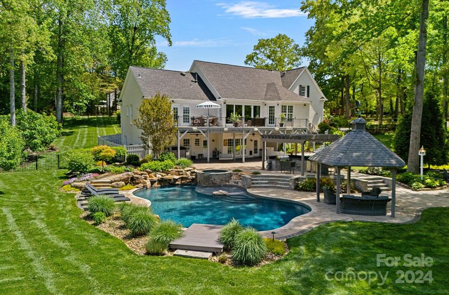 Experience the serene park-like setting at this meticulously renovated WATERFRONT home. Situated on a sprawling one and a half-acre lot, this home boasts a FOUR-CAR garage, stunning landscape design, and a brand-new outdoor oasis, featuring a custom pool, hot tub, fire pit, outdoor kitchen with pergola and swings, a gazebo, and a covered patio. Enjoy the convenience of a boat slip and two Jet Ski ramps. The charming painted brick exterior leads to main level living, featuring an open-plan kitchen and two-story great room, flex space, and dining room. The first-floor primary bedroom suite, with 2 walk-in closets, offers access to the main floor patio area. Additional bedroom and 5th bed/bonus upstairs. The basement hosts a game room, two additional bedrooms, and a full bath with direct access to the pool area. Just across the Iredell County border, benefit from lower taxes, many great choices for public and private schools, and convenient access to the I77 commute or scenic back roads.