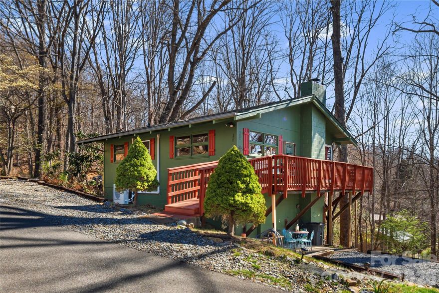 Tucked into a peaceful, wooded setting just moments from the tranquil waters at Lake Junaluska, this charming mountain retreat offers filtered views of the mountains through the trees and a true sense of escape. Inside, vaulted ceilings with warm wooden beams and a stately stone fireplace with gas logs create an inviting, cozy feel, while walls of windows fill the home with soft, natural light, creating an atmosphere that feels both airy and uplifting throughout the day. The main level opens to a spacious deck, perfect for relaxing and enjoying the fresh mountain air & features two comfortable bedrooms, while the finished basement offers incredible flexibility with its own kitchenette, living area, private driveway access, and covered patio; Ideal as a guest suite, bedroom, office, gym, art studio, or rental space for additional income. Conveniently located just minutes from downtown Waynesville, Great Smoky Mountain National Park, Blue Ridge Parkway, Cataloochee Ski Area & an easy 30-minute drive to Asheville, this home blends peaceful mountain living with everyday accessibility.