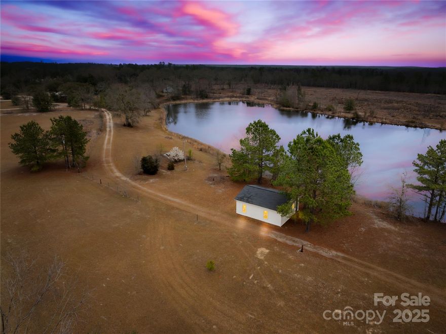 This Camden property offers over 66 acres of land with strong potential for equestrian, agricultural, or recreational use. The acreage includes open fields, wooded areas, and multiple locations suitable for barns, pastures, riding areas, or other improvements based on the buyer’s plans.
A 1,637 square foot ranch-style home sits on the property with three bedrooms and two bathrooms. It works well for on-site living or operational needs. A separate 1,000 square foot building, previously used as the Kershaw Library, provides flexible space for storage, office functions, or support use.
Two additional structures are on the property. One is a solid foundation intended for a future single-family home, offering a ready footprint for a buyer looking to build. The other is a framed shell for a two-bedroom, one-bath home. This structure gives buyers a head start on creating a guest house, staff housing, or another functional space.
A natural pond of about 3.5 acres adds scenic appeal and recreational value. The property sits along Kershaw Highway with short access to downtown Camden, the South Carolina Equine Trail, and I-20. The area is known for its active horse community and long equestrian tradition. Zoning supports agricultural and equine-related uses, giving buyers the flexibility to shape the property according to their goals.