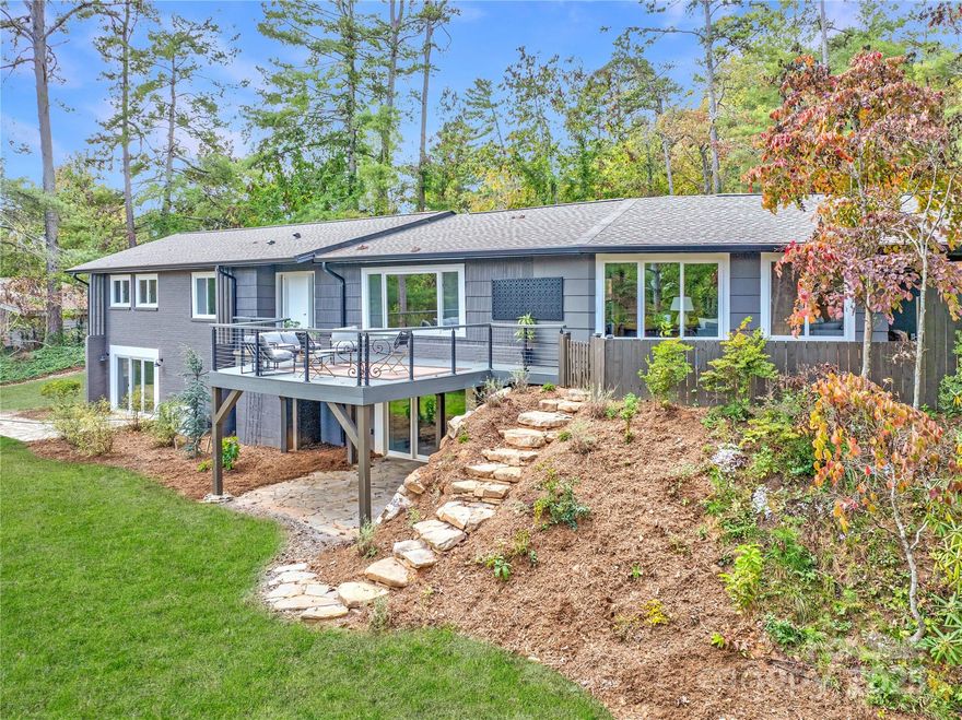Reimagined from the ground up, this southeast-facing Lakeview Park home blends modern design with contemporary mid-century warmth on a rare 0.74-acre corner lot that feels even larger thanks to its wooded buffer. Natural light fills the open main level, where hardwood floors, vibrant architectural color, and expansive windows frame lush, tree-lined views. The renovated kitchen is stylish and functional, designed for ease of use and connection to the home’s living and dining spaces. The main level maximizes living areas for everyday comfort and effortless entertaining. The flexible floor plan offers five bedrooms and four baths or four bedrooms plus a dedicated office. Upstairs, the main-level primary suite offers serene wooded views and a spa-like bath, accompanied by a second bedroom with an ensuite bath and a third room ideal for a bedroom or office. Downstairs, find two additional bedrooms, a den or flex space, and room for an office or media setup, offering ultimate versatility. Outdoor living is exceptional, with a fenced side yard and fire-pit area just off the living room, a back deck with peaceful wooded views, and private terraces/patios extending from the lower-level bedrooms, perfect for expansion, yard games, or gardening. This home balances craftsmanship, comfort, and creativity in one of Asheville’s most loved neighborhoods, just minutes from Beaver Lake, North Asheville’s shops and dining, and downtown Asheville. Don't miss this one! Book a showing today!
