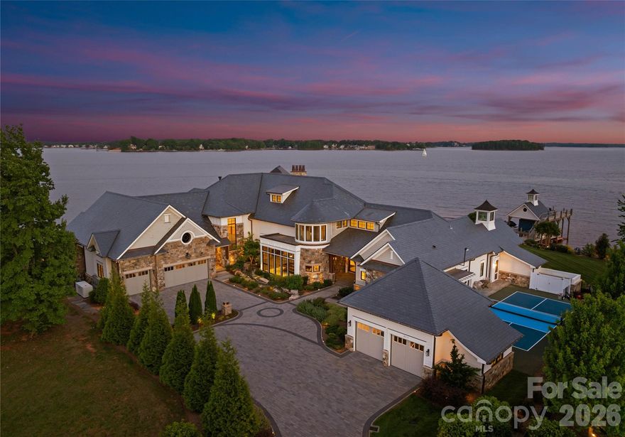 An architectural masterpiece designed by renowned architect Harry Schrader and custom built by Kingswood Custom Homes, this extraordinary waterfront estate represents the pinnacle of luxury living on Lake Norman. Positioned on a breathtaking peninsula point lot within the exclusive gated community of Norman Estates, the residence captures sweeping panoramic open-water views while delivering a rare blend of timeless design, exceptional craftsmanship, and resort-inspired amenities. Spanning more than 11,000 square feet, the home was thoughtfully designed to maximize natural light and seamless indoor-outdoor living through dramatic floor-to-ceiling windows and expansive entertaining spaces overlooking the lake. Sophisticated architectural details, curated finishes, soaring ceilings, and rich textures create an atmosphere that is both grand and inviting. Every element of the home was intentionally crafted to balance elevated entertaining with comfortable everyday living. The main level features a luxurious lakeside primary suite, elegant dining spaces, private office, fitness studio, billiards lounge, custom wine cellar, and a chef’s kitchen appointed with premium appliances and expansive gathering areas designed for effortless entertaining. Additional guest suites, media spaces, and custom bunk accommodations provide exceptional flexibility for hosting family and guests in comfort and style. Outdoor living rivals a private luxury resort with expansive covered terraces, vaulted entertaining spaces, a screened porch, built-in fire features, outdoor kitchen, manicured grounds, and a stunning infinity-edge pool and spa overlooking the waters of Lake Norman. A private dock complete with a boat lift, dual jet ski lifts, and upper-level sun deck further enhances the extraordinary waterfront lifestyle while maximizing the property’s breathtaking long-range lake views. Thoughtfully designed to feel equally suited for two as it is for hosting over 100 guests, the estate balances refined luxury with effortless livability. Curated for elevated living, the home also includes a regulation pickleball court, private theater, full entertaining bar, five-car garage, whole-home generator, surround sound, and security system. Offered fully furnished and turnkey, this is a once-in-a-generation opportunity to own one of Lake Norman’s most iconic and architecturally significant waterfront estates.