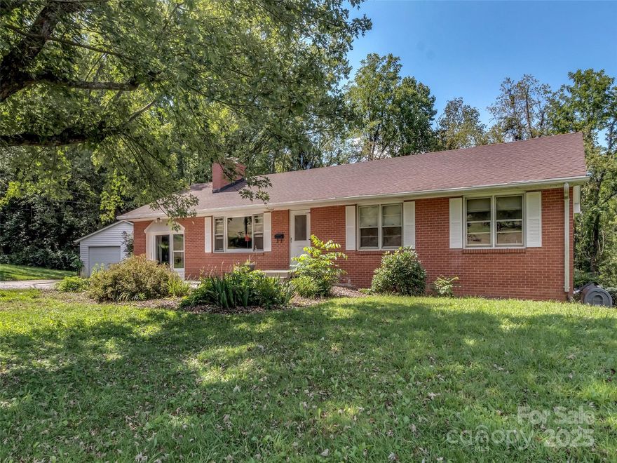 Welcome home to this classic brick ranch situated on over 1 acre of level, usable land in beautiful Canton, NC! With real hardwood floors, a newer roof, updated septic system, and new garage doors, this property offers both comfort and peace of mind. Enjoy the creek, surrounded by mature trees and vibrant flowers that bloom seasonally. The detached 2-car garage and large unfinished basement provide ample storage, workshop potential, or room to expand. Conveniently located less than 5 minutes to I-40 and local grocery stores, you're also just a short drive from the charm of Waynesville and the vibrant culture of Asheville. Whether you're looking for a peaceful retreat or a place to grow, this home offers a perfect blend of location, land, and lifestyle. Don’t miss your chance to own a piece of the mountains with modern updates and timeless appeal.