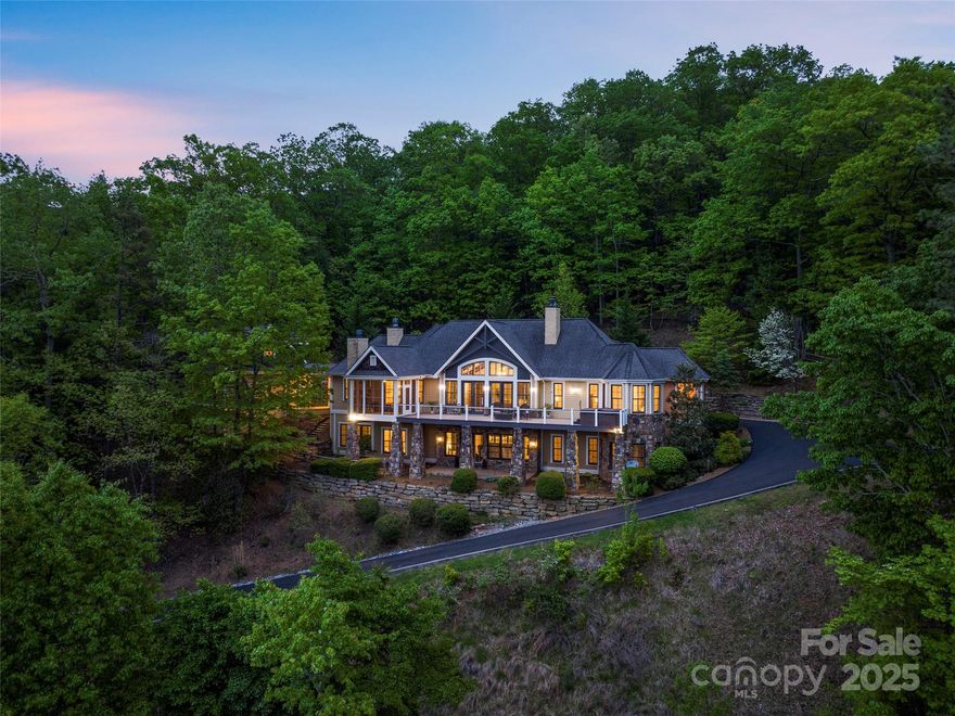 Perched high along the ridgeline of the Biltmore Lake community, this stunning mountain estate showcases panoramic, long-range views of the awe-inspiring Blue Ridge Mountains from nearly every room. Crafted to the highest standards, the main level features a dramatic great room anchored by a stone fireplace, a gourmet kitchen and a gracious dining room with its own fireplace. The luxurious main level primary suite offers a peaceful haven with a private sitting area and deck access. The terrace level provides a second primary suite, two guest bedrooms, and a generous recreation room complete with a stone fireplace and wet bar. Above the three-car garage, a private guest suite offers the perfect accommodations for family or visitors. Backing up to the 138-acre Scott’s Ridge conservation preserve, this exceptional home is just steps away from miles of scenic hiking and biking trails, along with all the resort-style amenities that make Biltmore Lake one of WNC’s most desirable communities.