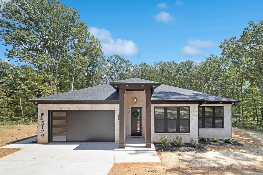 Presenting the Signature Series by Northway Homes, where timeless elegance meets modern convenience. This exquisite all-brick home features 3 bedrooms and 2 bathrooms, embodying superior craftsmanship and thoughtful design. Upon entry, you’re greeted by hardwood floors that flow seamlessly throughout, creating a warm and welcoming atmosphere. The kitchen serves as the heart of the home, complete with quartz countertops, a custom tile backsplash, and premium appliances. An electric fireplace adds a touch of sophistication to the living area, while 10-foot ceilings amplify the sense of space. The primary suite is a private haven, featuring an ensuite bath that offers both luxury and comfort. Sliding double glass doors effortlessly connect the interior to the expansive back deck, perfect for outdoor enjoyment. Set on a generous 1.3-acre lot in Lincolnton, NC, this home offers privacy and space!