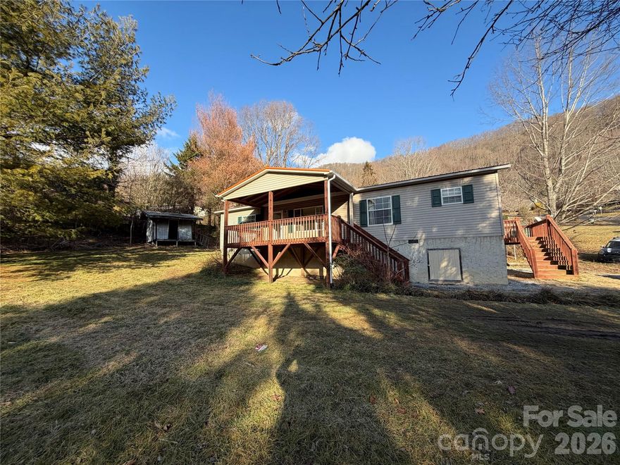 2008 3 BR, 2 bath Doublewide situated on a gently sloping  .63 ac lot in Maggie Valley. Wood burning fireplace, vaulted; ted ceilings in LR, 2 car carport, small outbuilding and dog lot, Covered front porch, large back deck and smaller side deck, metal roof, heat pump.