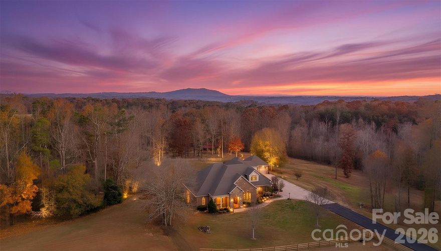 Welcome to a truly special private equestrian estate set on over 9+/- beautiful acres in Catawba County, where custom craftsmanship, thoughtful design, and exceptional outdoor living spaces create a lifestyle property that is both refined and functional. Tucked away from the road and surrounded by rolling pasture and peaceful countryside views, this impressive property offers the perfect blend of privacy, space, and convenience while still being just a short drive to Hickory, Newton, and surrounding amenities. From the moment you arrive, the home’s custom architectural details and welcoming presence immediately stand out. A beautifully crafted custom front door, detailed trim work, and striking rock accents highlight the quality construction and thoughtful upgrades throughout the home. Inside, spacious living areas are filled with natural light and designed for both everyday comfort and entertaining. The main living space offers a warm and inviting atmosphere with beautiful finishes and views of the surrounding property. Just off the main living areas, a dedicated office provides the perfect space for working from home or managing daily tasks in a quiet and private setting. The kitchen and dining spaces flow effortlessly together, creating a natural gathering place for family and guests. With generous cabinetry, ample counter space, and room for entertaining, this area truly serves as the heart of the home.
The primary suite offers a private retreat with abundant space and comfort, highlighted by two large walk-in closets and a spacious en-suite bath designed for relaxation. Additional 3 bedrooms provide flexibility for family or guests, while the home’s media room and bunk room/bonus space create the perfect environment for movie nights, play space, or hosting overnight visitors. Designed with lifestyle in mind, this home offers multiple outdoor entertaining areas where you can enjoy the peaceful surroundings and beautiful views of the property. Whether gathering with friends, hosting family celebrations, or simply enjoying quiet evenings outdoors, the outdoor spaces extend the living experience well beyond the home itself. For those who appreciate both storage and functionality, the property features an attached oversized three-car garage along with an additional detached two-car garage, providing plenty of room for vehicles, recreational equipment, hobbies, or workshop space.
The nearly 10 acres of land create the ideal setting for equestrian use or country living, offering space for horses, pasture, and endless outdoor possibilities. With open land and room to expand, the property offers incredible flexibility for those seeking a rural lifestyle while maintaining easy access to town- 2 Barn Structures on the property. Properties that combine custom homes, equestrian potential, acreage, and thoughtful upgrades are increasingly rare in Catawba County. This exceptional estate provides the opportunity to enjoy privacy, comfort, and the beauty of the countryside all in one remarkable property. Come experience the space, craftsmanship, and lifestyle this unique property has to offer.