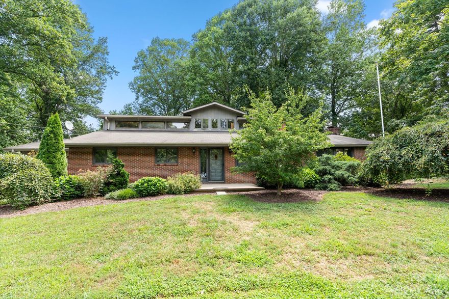 Investor ALERT!  Massive brick home with enormous potential. Nestled in a quiet community just minutes from Asheville and Woodfin, this home sits comfortably on 1.79 acres of cleared land.  This sprawling home was custom built and kept in the family for generations until now.  The spaces are many with a large great room with wood burning fireplace and tons of light. The sunroom extends almost the entire house with an additional covered deck. The primary bedroom is larger than most living rooms. Upstairs is a loft/bedroom with crank windows to let in the breeze. In the basement you will find a two car garage, additional living space with fireplace, another bedroom and bath and tons of storage. The possibilities are endless!