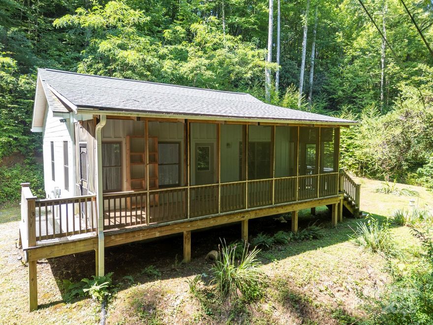 Great things come in small packages! This adorable 1 bed, 1 bath cottage, built in 2016, offers quality construction and a thoughtfully designed open floor plan. The compact yet functional kitchen maximizes space, while the spacious 240 sq. foot covered and screened porch invites you to relax and enjoy outdoor living. The efficient kitchen is open to the living space and features North Carolina granite. The spacious bedroom features a roomy walk-in closet and ensuite bath with lovely tiled walk-in shower.  The laundry room boasts sturdy wooden shelves for additional pantry storage. Nestled on a peaceful property with a soothing creek nearby—close enough to enjoy the sound but not a flood risk.  A fenced area provides added security, and with no HOA fee or city taxes, this gem is perfect for year-round living or a mountain getaway. Ample parking and easy turnaround! Just minutes to downtown Waynesville and Hazelwood’s award winning dining and shopping. Your mountain dream awaits!