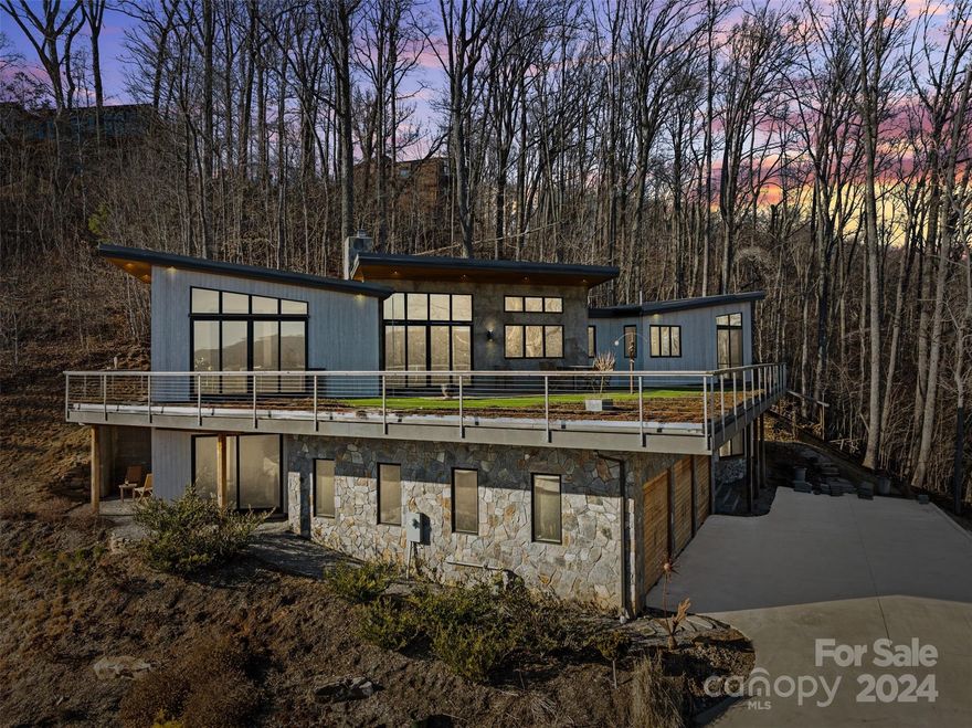 Experience the perfect blend of modern luxury and artistic chic in this one-of-a-kind custom built contemporary Estate home. Enjoy unobstructed sweeping mountain views from the floor to ceiling light filled windows and the generous wrap-around "living green" deck, an ideal setting for indoor/outdoor living, gatherings, dining and leisure. Luxury meets artistic integrity with features like the custom steel stair-railing by renowned artist Steebo, artisan created live edge walnut swivel entry door, modern polished concrete and hickory floors. This home also boasts a 1,344 ft 3-car garage, gourmet kitchen with Thermador appliances, stunning custom live edge maple island, quartzite counter tops, hand blown lighting fixtures, an abundance of solid hardwood cabinets, an open living concept and so much more, (see in attachments). No need to traverse winding roads to get to these outstanding views, only 2 miles to downtown Asheville's award winning restaurants and distinctive shopping.