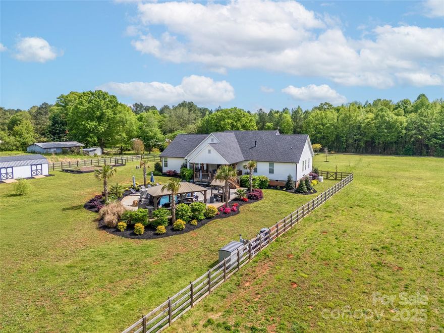 Just minutes from Waxhaw and Indian Land, this 1-story, 4-bed, 3.5-bath home with a 3-car oversized garage spans 2.5 acres, blending luxury and farmhouse charm. The chef’s kitchen with huge island overlooks a family room with a gas fireplace. The primary suite features a luxe bathroom with a tile shower and soaking tub. Enjoy a gas-powered whole-house generator and a large mudroom with a dog washing station. If you are looking for easy maintenance, there is no carpeting in this home. The covered back porch overlooks an entertainer’s dream: a zero-depth heated pool, rock waterfall, large concrete pool deck for lots of chairs and pavilion with stone fireplace with a big counter and room for a big table to host epic parties. Huge fenced back yard with separate garden area and oversize gardening shed. On 2.5 acres (aprox- the property is in the process of being subdivided), this gem offers privacy and endless possibilities! Home has been meticulously taken care of. Move in and enjoy!