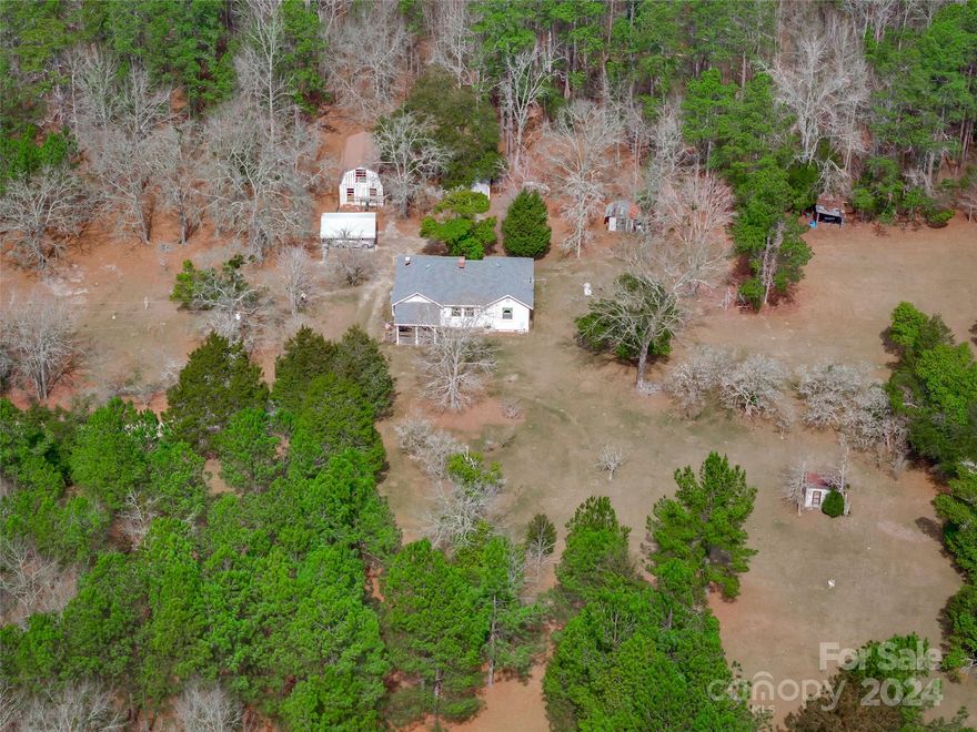 2324 Dekalb School Rd in Camden, SC is a private oasis. Nestled on 31.48 acres, this 1413 sqft home features 3 bedrooms & 1 bath, wood burning fireplace, workshop & outbuildings. The interior reflects a classic design with vintage details. Keen buyers should note that the roof was replaced in 2018 & a new septic tank & drain fields were installed in 2022. The property unfolds with a classic barn that once housed 2 horses with additional space for hay & tack. Currently in need of TLC, it could be reused for this purpose again, converted to use for livestock or farm storage. The property also includes a 2 story workshop that is perfect for hobbyists or craftsmen seeking a dedicated space for their pursuits. Large hand hewn beams give the workshop a rustic and historic appeal. Other small outbuildings provide storage. The topography is mostly level land, with wooded & cleared areas. Whether cultivating gardens, hunting or exploring nature, the possibilities are as vast as the land itself.