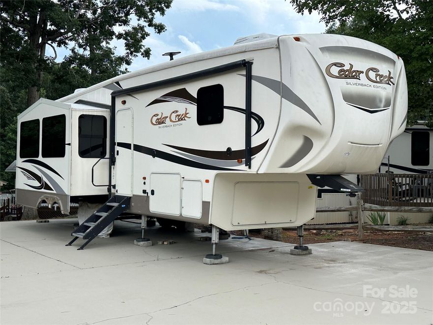 Escape to Lake Life! This 2018 Cedar Creek fifth wheel is set up on a deeded lot inside the waterfront community of Badin Shores Resort at Badin Lake. Enjoy a spacious and stylish interior featuring a large living area with a sofa, reclining loveseat, electric fireplace, and mounted TV. The kitchen boasts stainless steel appliances, a dual-door refrigerator, and a large island with a dual-basin stainless sink, ideal for cooking and entertaining. The bedroom offers storage, a washer/dryer combo, and the bathroom includes a step-in shower. A new A/C unit was installed in 2024.  The low-maintenance lot features a large concrete pad, perfect for outdoor gatherings, plus a storage building for all your lake gear. Just a short distance to many of the community amenities including the swimming pool, putt-putt course, basketball and sand volleyball courts, playground, community pond, and pavilion. Whether you’re looking for a weekend retreat or a seasonal escape, this is lake living made easy!