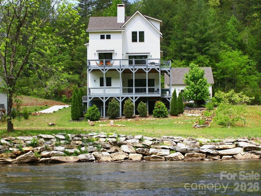 This luxurious modern farmhouse is perfectly situated above the tranquil Tuckasegee River, a fisherman’s dream stocked with trout and perfect for floating or kayaking directly from your backyard. The gently sloping, oversized lot offers one of the most desirable settings in the neighborhood, with a large grassy backyard, no flood damage during Hurricane Helene, and plenty of parking for family and guests. Inside, the home features a spacious open floor plan with beautiful river views from nearly every window. The main level includes a large living room that flows into an elegant kitchen and dining area with a half bath. From here, step onto one of two expansive Trex decks, ideal for lounging and entertaining while overlooking the river. The upper level serves as a true retreat, with a primary bedroom that opens into a spacious office with a sleek wet bar, a private Trex deck, and a spa-like bathroom with a soaking tub and tiled shower. The third floor includes two generous guest bedrooms, each with its own private full bathroom. A Redwood Outdoors 6-person barrel sauna, featuring a powerful 8kW Harvia WiFi-controlled heater and a full glass wall that looks out over the water, creating a private wellness experience. The home also offers a large covered front porch, an oversized two-car garage with an unfinished upstairs, and tasteful stone landscaping that ties everything beautifully into the upscale neighborhood. Built with 2x6 construction, the home includes industrial-grade LVP flooring throughout, with durable carpet on the stairs. The design blends premium craftsman style with modern farmhouse touches. It comes fully furnished (excluding a few select pieces) and includes high-end appliances such as a washer, dryer, and refrigerator. The kitchen features premium Miele appliances, including the oven, microwave, and dishwasher. Enjoy the benefits of natural gas, including a gas stove and a grill hookup. The property is also connected to high-speed fiber internet, making it ideal for remote work or streaming. Located just seconds from the Western Carolina University campus, this home offers both convenience and privacy. The community allows select short-term rentals, and this property is one of the few that qualifies. Other similar rentals in the neighborhood have a proven track record of profitability, while the remaining homes are owner-occupied family residences. This is a rare opportunity to own a premium riverfront home with unmatched views, luxurious features, and income potential!