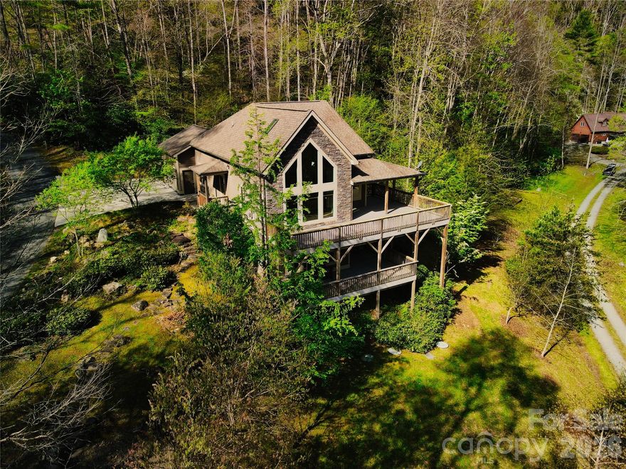 RIVERSONG — Where the river sets the rhythm of your days.
Some homes have a soundtrack. At Riversong, it's Big Laurel Creek — visible through floor-to-ceiling windows, audible from every deck, and just steps from your door. Tucked at the end of a private road in Bear River Lodge, bordered by Pisgah National Forest, this 2014-built creekfront home delivers soaring ceilings, a stacked stone fireplace, open kitchen with island and granite counters, and mountain and water views that never get old. The main level hosts two bedrooms, two baths, and a covered porch. A loft with adjacent unfinished space offers exciting possibilities above. The finished lower level — live edge bar, family room, bonus room, full bath, and walkout deck — is yours to define. STRs permitted, serenity delivered.
Come hear what Riversong is named for.