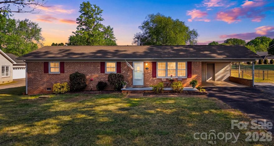 Welcome to this wonderfully maintained brick 3BR/2BA ranch, perfectly situated in a serene, quiet country setting while still offering an easy drive to Hickory and convenient access to shopping and dining in Taylorsville. This inviting one-level home features minimal entry with just a single step inside, making everyday living effortless. Relax on the charming rocking chair front porch before stepping into a spacious living room filled with warmth and comfort. The kitchen has been thoughtfully updated with newer appliances and offers bar seating—perfect for casual meals or gathering with friends and family. The home is equipped with a heat pump installed in 2021 for added efficiency and peace of mind. A cozy wood-burning stove adds character and an extra touch of comfort during cooler months. Step outside to enjoy the large, level backyard—ideal for entertaining, gardening, or simply unwinding. The patio provides a great space for grilling and relaxing, while the newly added 60x90 fenced area offers versatility for pets or outdoor activities. Two spacious outbuildings provide excellent storage or workshop options. This well-cared-for home blends comfort, functionality, and a peaceful setting—don’t miss your opportunity to make it yours! This property is within 1/2 mile of a voluntary agriculture district.
