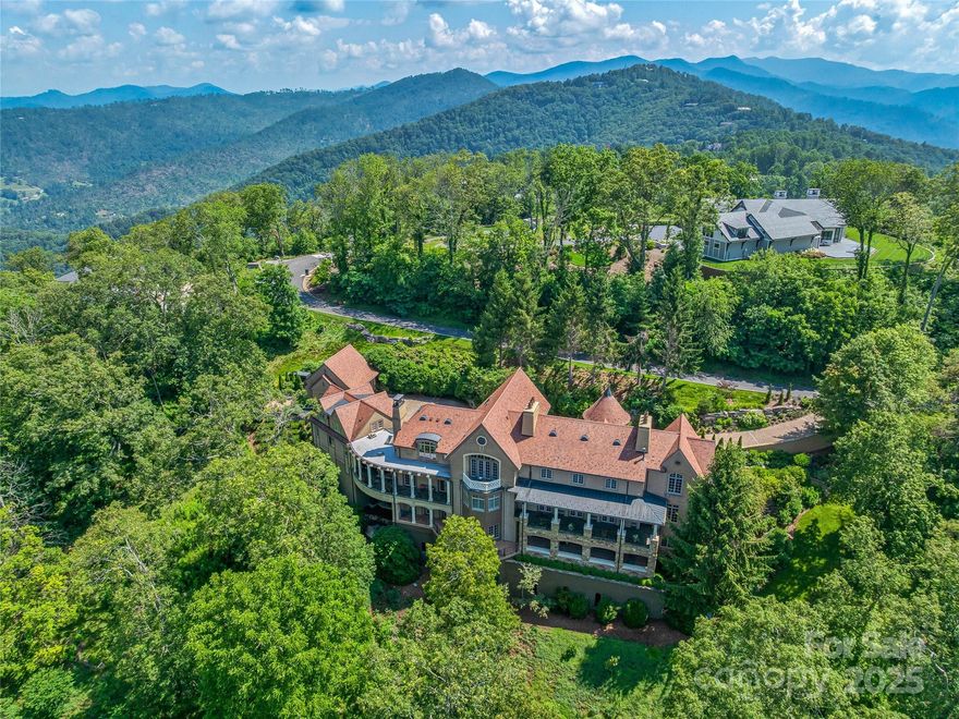 This luxurious European-inspired home has breathtaking views of the Blue Ridge Mountains and is ideally located just miles from downtown Asheville. Meticulous craftsmanship and opulent finishes are showcased throughout, including Italian limestone fireplaces, custom ironwork, and a striking Verdi Fire granite kitchen island. Elegant flooring of quarter-sawn oak, marble, and Jerusalem limestone enhances the home's sophisticated ambiance.
Designed for both comfort and grandeur, the home offers seamless spaces for private relaxation and lavish entertaining. The primary suite features a private balcony with panoramic mountain views, while the en-suite bathroom exudes elegance with marble floors and intricate medallion accents. A private grotto with a poured gunite hot tub and cascading waterfall creates a serene, spa-like retreat. Wine connoisseurs will appreciate the climate-controlled wine cellar, and film lovers can indulge in the custom home theater with luxurious leather seating.
