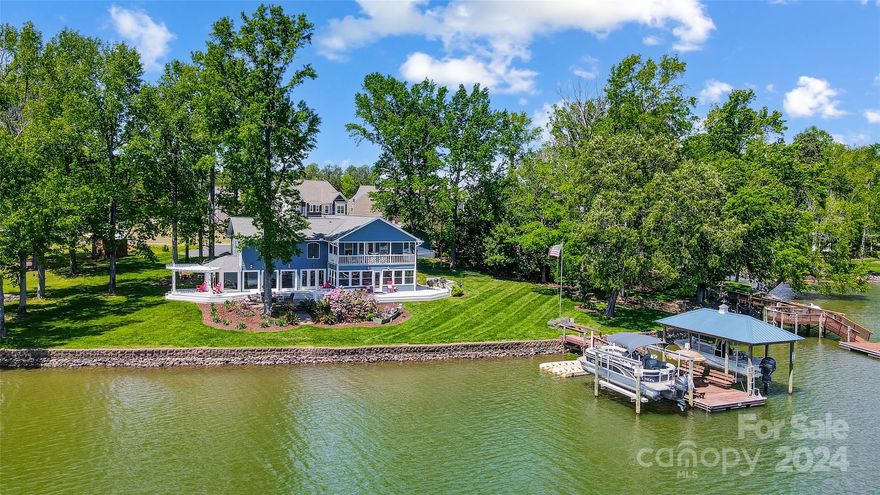 Enjoy captivating views from almost every room in this waterfront treasure. Designed to enjoy lake living & the outdoors, this beautiful home features rare level lot with +/- 250' of shoreline along the Snug Harbor section of Lake Wylie. The large deck, paver patio, & spacious lawn are perfect spots for entertaining or just to relax & take in the view. Covered dock w/ 2 boat lifts, jet ski ports, & boat ramp ready for your lake adventures.  Indoors you'll find an open floor plan featuring tons of natural light, beautiful floors, home office, & amazing views. Kitchen boasts ss appliances, gas range, granite counters opening to dining area, sunroom, & great room! Main level primary suite with sitting room & spa-like bath. Upper level features 2nd BR, bonus/bedroom(w/ wet bar & private balcony), & unfinished storage room for possible future expansion. Detached garage w/workshop is ideal for storage & lake toys. Located next to The Palisades, where golf & tennis memberships are available.