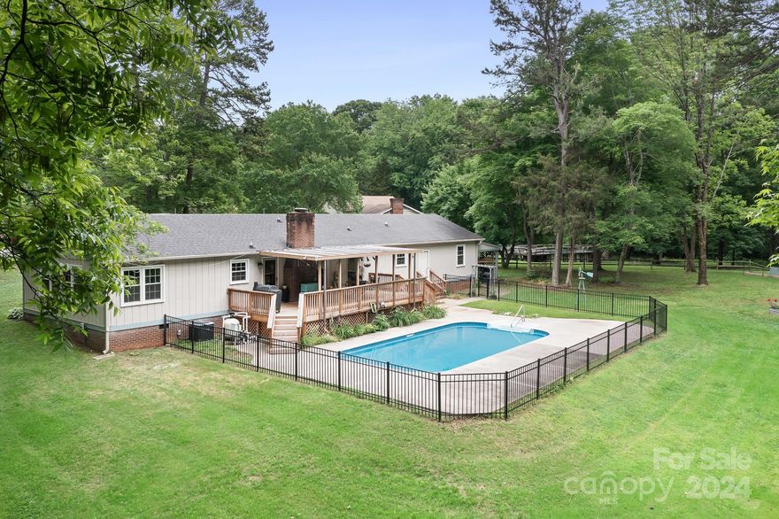 Country Setting with almost an acre lot! Backyard feels like a resort with a beautiful sparkling in-ground Saltwater pool with extra cement surround. Large covered deck overlooking pool and trees. Huge yard space backs to trees.  Oversized fire-pit perfect for fall evenings! Guest House with studio style living space, full kitchen and full bathroom! Approx 512 Sq. Feet.  Main home features vaulted ceilings in living room, breakfast bar in kitchen and woodstove in family room! New Luxury Vinyl Plank flooring throughout! New plumbing and Vinyl Windows too!  Front porch is perfect for rocking chairs and summer nights!  Large 2 car garage and carport attached too. New Water Softers in Garage.  Amazing Huge Raised Garden ready for your plantings this summer! 4th Bedroom and 3rd bath are part of the studio/guest house.