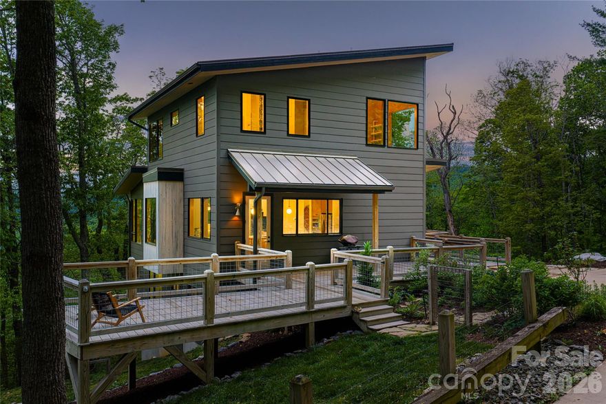 Set at the end of a quiet cul-de-sac in the Glen Merrill neighborhood of South Asheville, this modern mountain retreat is a rare expression of privacy, light, and landscape. A long, winding approach sets the tone—offering a sense of arrival that feels both serene and removed, while unveiling breathtaking, layered mountain views that define the home’s setting.
Designed to embrace its natural surroundings, expansive decks extend the living spaces outdoors, inviting morning coffee at sunrise and evenings framed by ever-changing skies. Inside, a thoughtfully designed drop zone provides everyday convenience, while the main level unfolds into an open-concept living space that is both refined and welcoming. The kitchen, dining area, and living room flow seamlessly together, anchored by warm wood floors and surrounded by generous windows that flood the home with natural light and bring the outdoors in.Upstairs, the private primary suite offers a peaceful sanctuary, complemented by a versatile bonus room ideal for a studio, lounge, or additional workspace. The lower level expands the home’s livability with two bedrooms, two bathrooms, a recreation area, dedicated office, and a well-appointed laundry room—perfectly suited for guests or multi-generational living.
A detached one-car garage adds to the property’s functionality, while the surrounding landscape ensures a sense of quiet seclusion rarely found so close to Asheville’s vibrant offerings. This is a home where modern design meets mountain tranquility—crafted for those who value both connection and retreat.
Extensive private trail system throughs out the acreage in this incredibly convenient location in South Asheville.