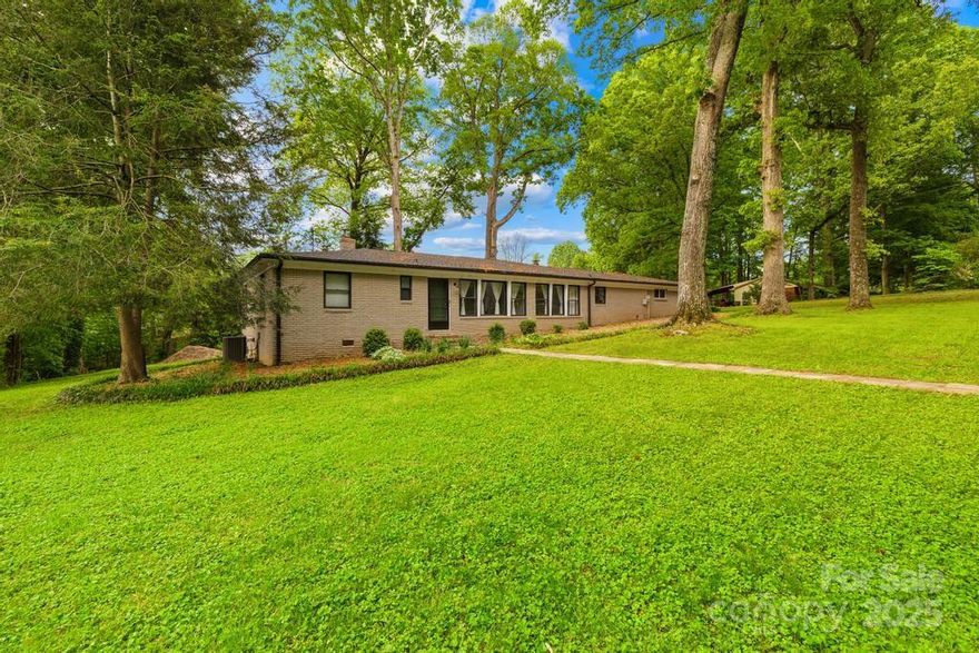 Nestled on a spacious, level .57-acre corner lot in Grove Park, this 3 bed/3 bath ranch blends classic charm with thoughtful upgrades. Step into open, sun-filled spaces featuring original hardwood floors and graceful arches. The inviting kitchen boasts granite counters, SS appliances, new microwave and dishwasher, tiled backsplash, and flows seamlessly into a cozy dining area accented by a striking mid-century brick fireplace. Relax in the private primary suite with updated bath and ample closet space. Enjoy 2 additional bedrooms, 2 full baths, den, and office space! Opposite side hosts a generous 350 sqft bonus room ideal for hobbies or entertaining. Outdoors, enjoy privacy on the expansive deck, perfect for gatherings, overlooking a lush yard with fire pit, mature trees, and storage shed. Practical features include large laundry, driveway parking, and no HOA! EV Charger to convey. Grove Park offers scenic lakes, parks, and is conveniently close to Charlotte amenities.